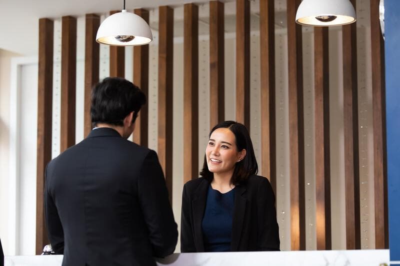 Friendly receptionist woman working at desk in hotel lobby. Leisure and travel at holidays.