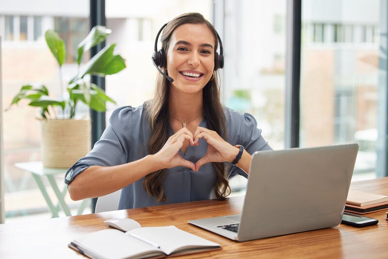 Woman, call center and laptop with heart gesture for telemarketing, customer service or support at the office. Portrait of happy employee consultant with smile and hands with love symbol by computer